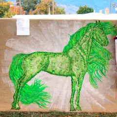 A vibrant green horse painting on burlap, flanked by American flags.