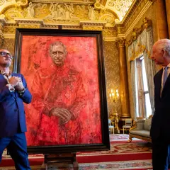 Artist and King Charles III stand by a striking red portrait. This artwork is one of what are some ways the king's portrait was used?