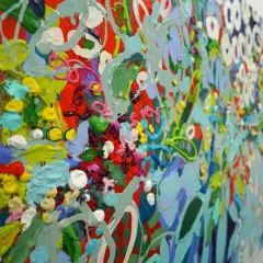 A vibrant, detailed abstract art piece explodes with thick, textured paint in shades of red, green, blue, yellow, and pink, creating a lively, energetic composition.