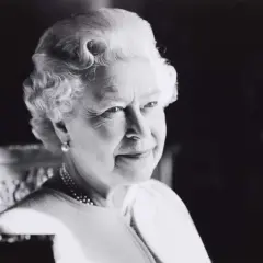 A classic Sutherland portrait of the Queen, her gaze thoughtful, adorned with pearls and a subtle smile.