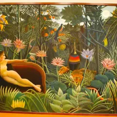 A woman reclines in a lush jungle, surrounded by exotic flowers and watchful lions. This is a classic example of Henri Rousseau's jungle paintings, filled with vibrant colors and a dreamlike atmosphere.