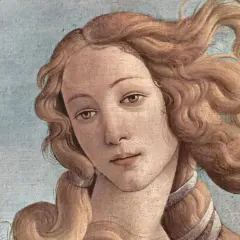 The face of Venus, a timeless muse in art, with flowing golden hair against a pale blue sky.