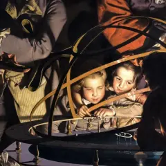 Children gaze at an armillary sphere, their faces illuminated by a dramatic tone in art. A woman in a hat watches intently.