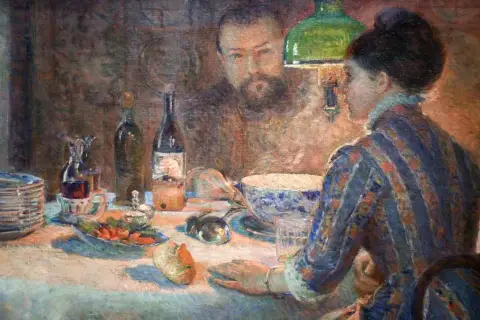 A woman in a striped dress sits at a table laden with food and drink, her gaze directed towards a man reflected in the background. This scene captures the essence of Marie Bracquemond's artistic vision.
