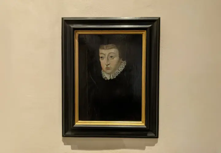 A dark portrait of Catherine de Medici, her gaze direct, framed by a ruffled collar and a dark headdress.