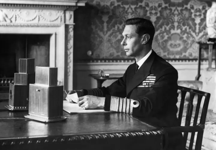 King George VI portrait: The monarch, in naval uniform, sits at a desk, holding a letter.