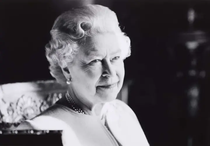 A classic Sutherland portrait of the Queen, her gaze thoughtful, adorned with pearls and a subtle smile.