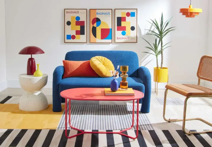 A living room showcasing bauhaus design examples: a blue sofa, geometric art, and colorful furniture.