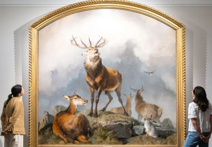 Two women admire a dramatic painting of a stag, deer, and rabbits, reminiscent of Edwin Landseer paintings, in a gallery.