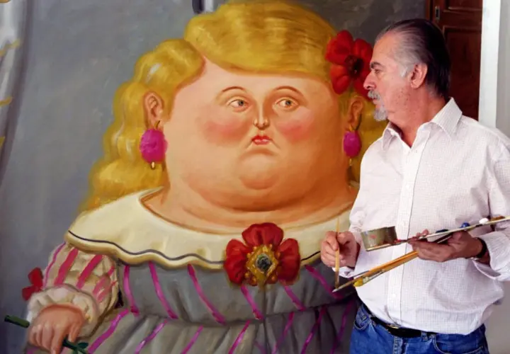 Artist Fernando Botero with a palette and brushes, standing next to a painting of a voluptuous woman in his signature style.