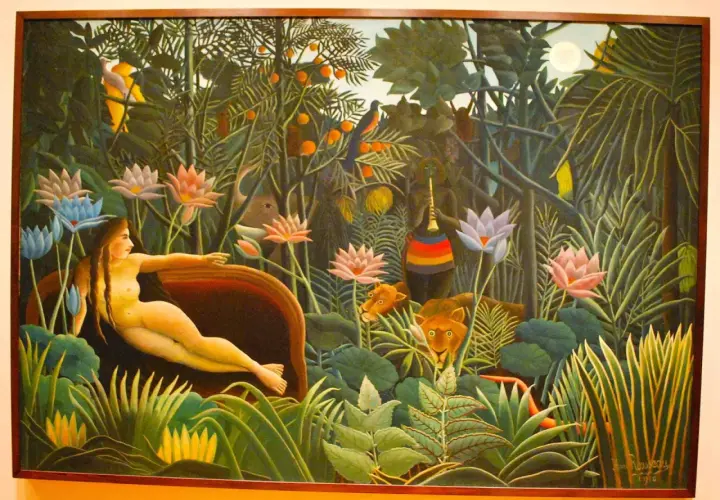 A woman reclines in a lush jungle, surrounded by exotic flowers and watchful lions. This is a classic example of Henri Rousseau's jungle paintings, filled with vibrant colors and a dreamlike atmosphere.