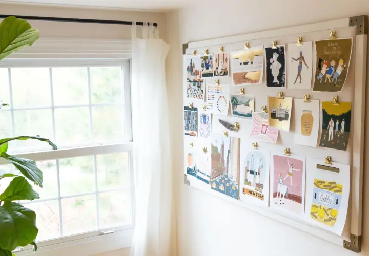 A mood board displays a collection of minimalist contemporary art prints, featuring cityscapes, figures, and whimsical illustrations, all clipped to a white board.