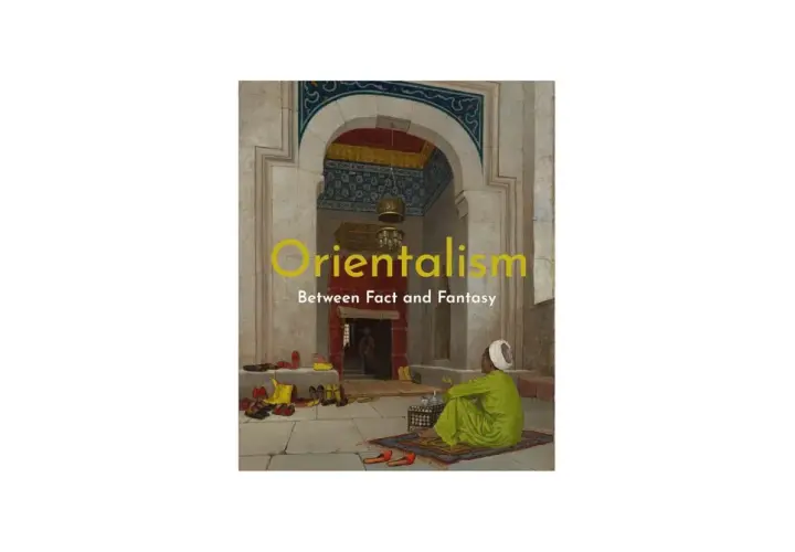 A man in a green robe sits on a rug in an ornate archway, a scene evoking orientalism art. Shoes are neatly arranged on the stone floor.