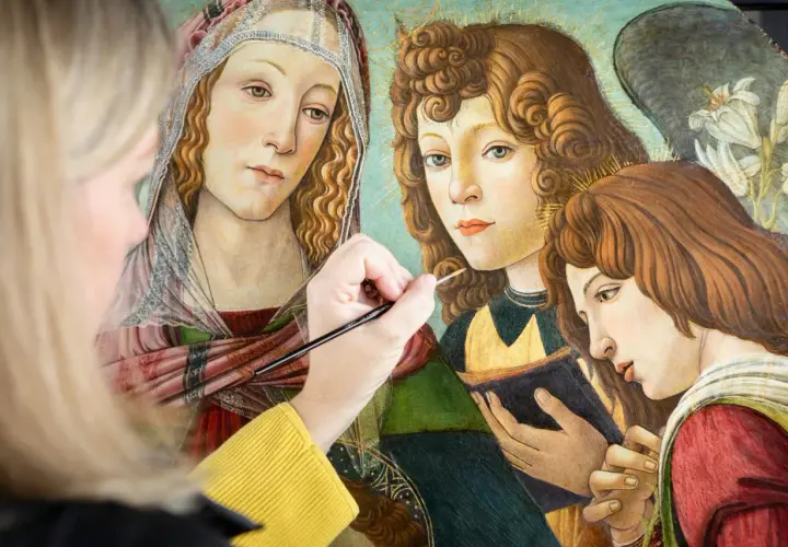 A modern artist meticulously restores a Renaissance painting, bringing to life the delicate details of angelic figures.