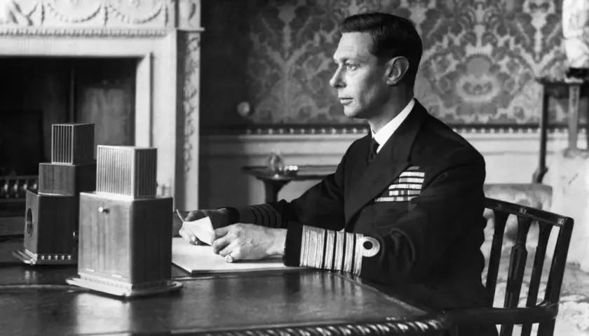 King George VI portrait: The monarch, in naval uniform, sits at a desk, holding a letter.