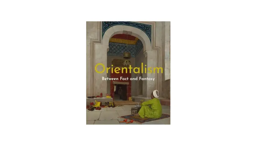 A man in a green robe sits on a rug in an ornate archway, a scene evoking orientalism art. Shoes are neatly arranged on the stone floor.