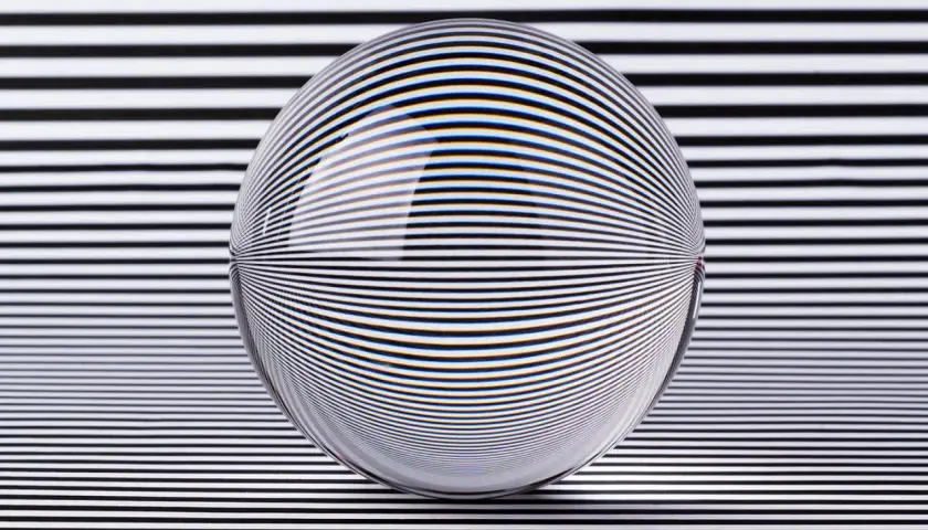 A glass sphere distorts black and white stripes, creating a mesmerizing optical illusion art piece.