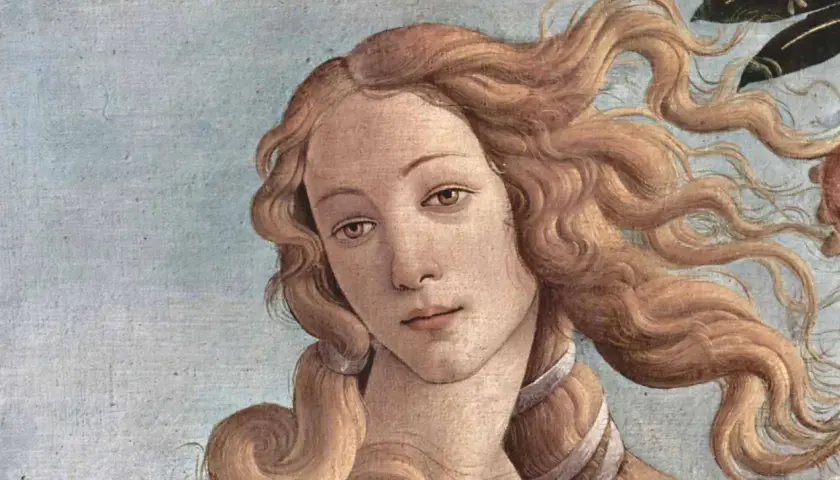The face of Venus, a timeless muse in art, with flowing golden hair against a pale blue sky.
