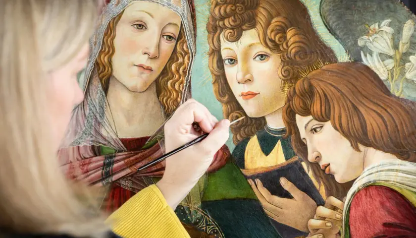 A modern artist meticulously restores a Renaissance painting, bringing to life the delicate details of angelic figures.