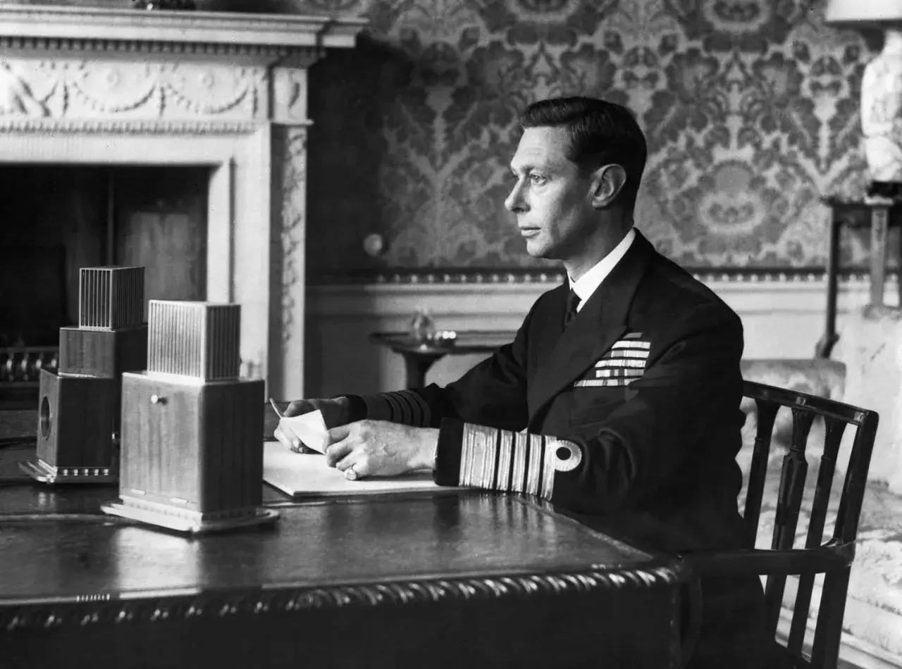 King George VI portrait: The monarch, in naval uniform, sits at a desk, holding a letter.