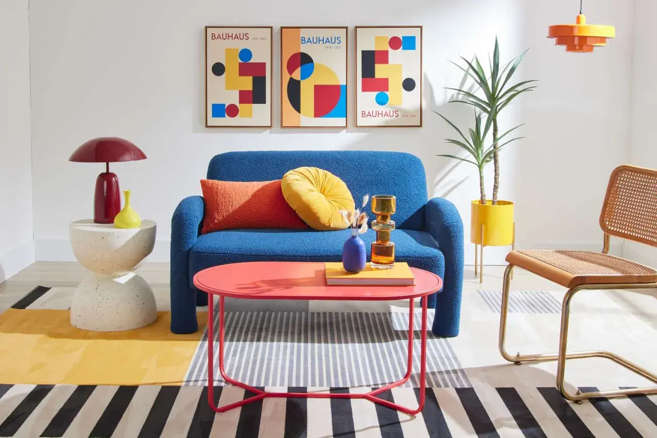 A living room showcasing bauhaus design examples: a blue sofa, geometric art, and colorful furniture.