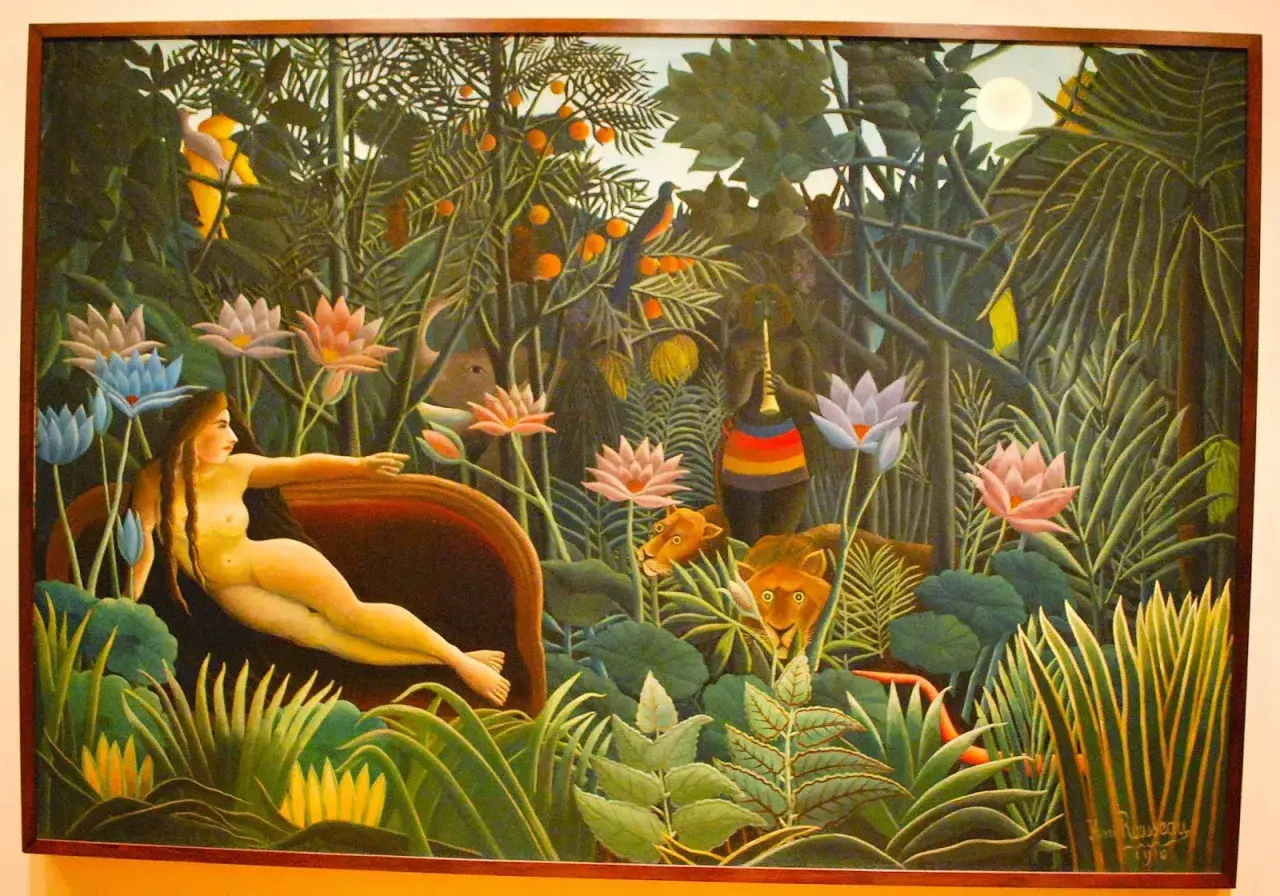 A woman reclines in a lush jungle, surrounded by exotic flowers and watchful lions. This is a classic example of Henri Rousseau's jungle paintings, filled with vibrant colors and a dreamlike atmosphere.