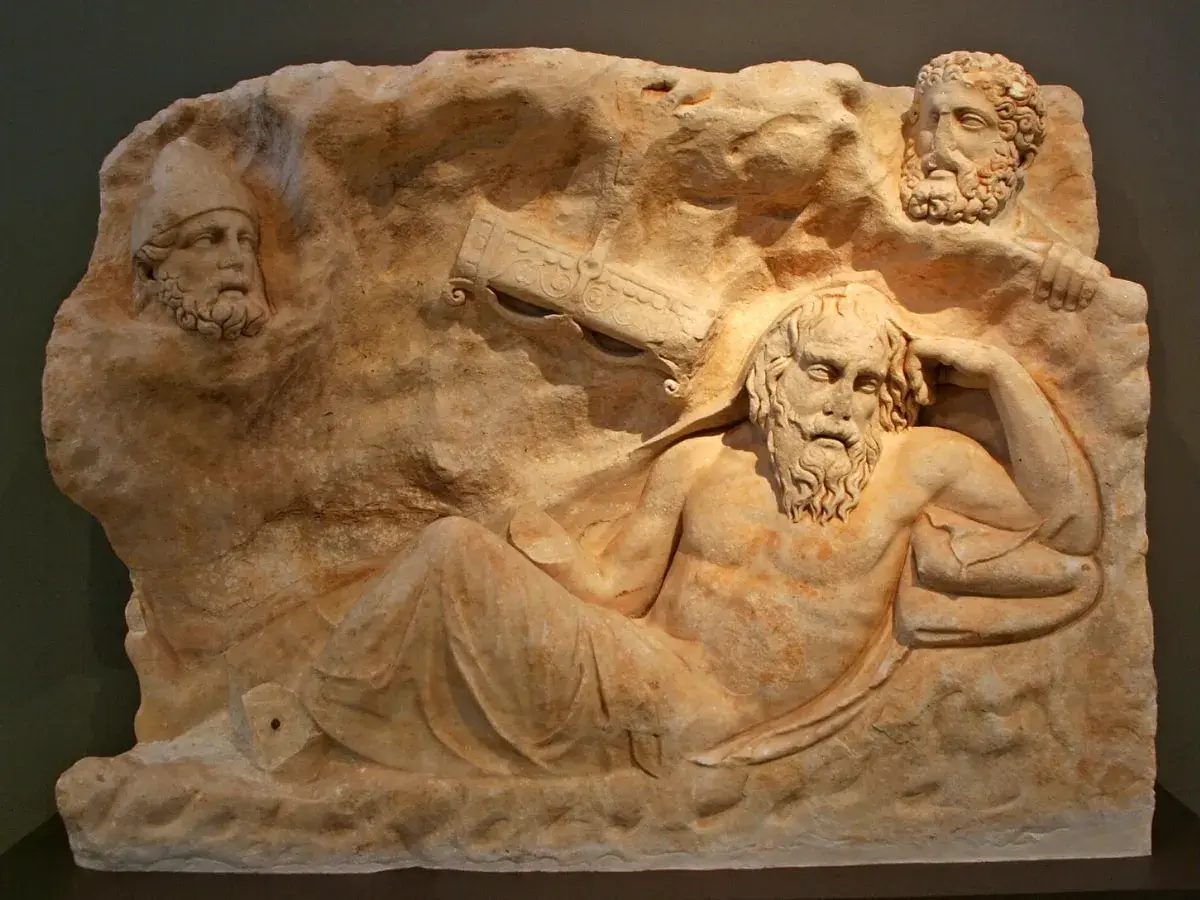 Relief sculpture depicts the wounded Philoctetes, abandoned and suffering, with two other figures observing him from above.