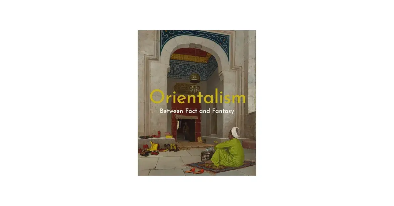 A man in a green robe sits on a rug in an ornate archway, a scene evoking orientalism art. Shoes are neatly arranged on the stone floor.