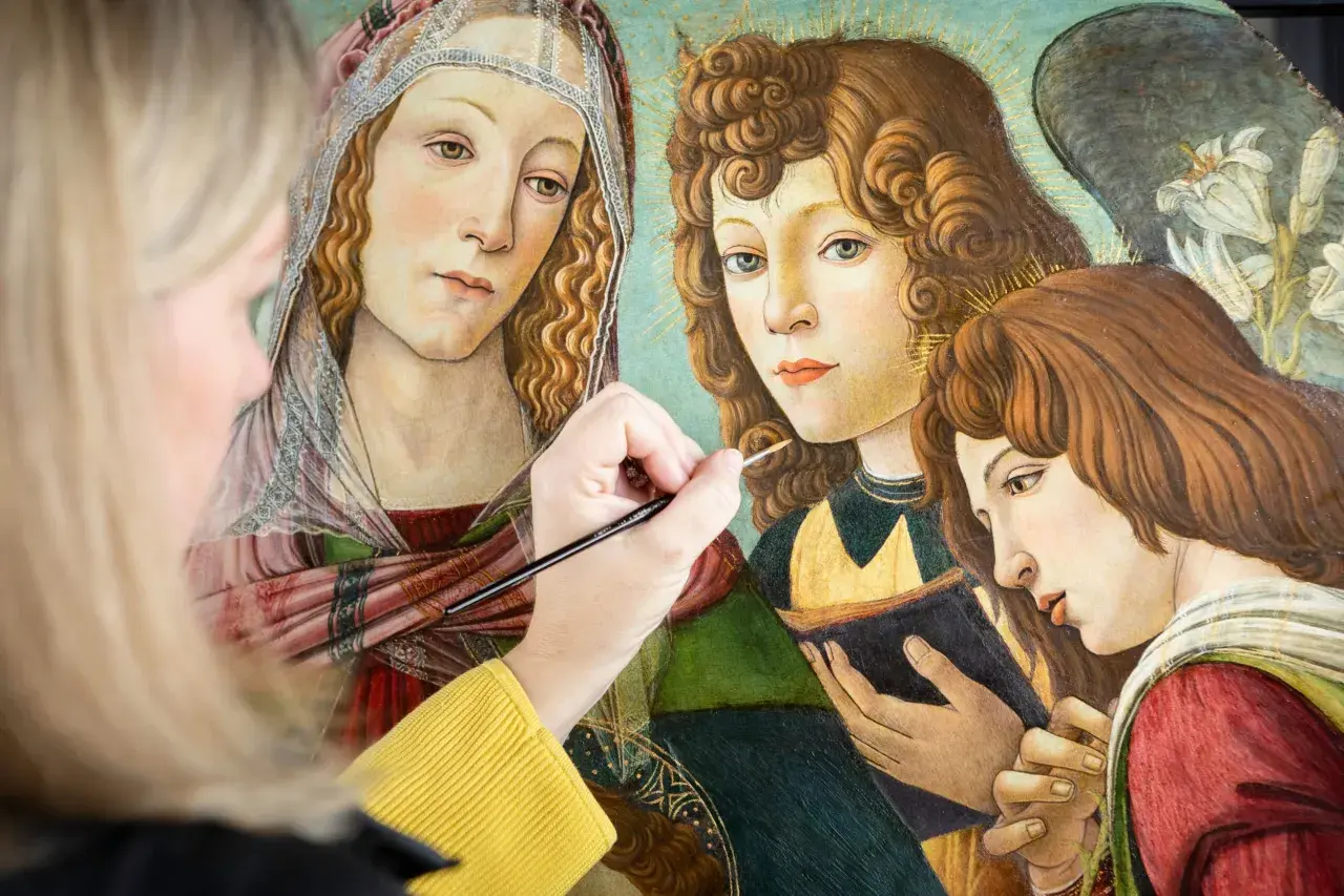 A modern artist meticulously restores a Renaissance painting, bringing to life the delicate details of angelic figures.
