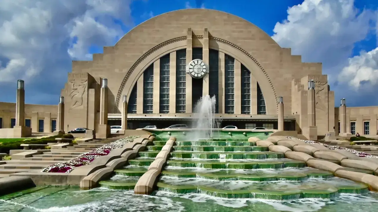 A grand fountain cascades down tiered steps before a monumental building, showcasing the geometric symmetry and stylized reliefs that define art deco architecture.