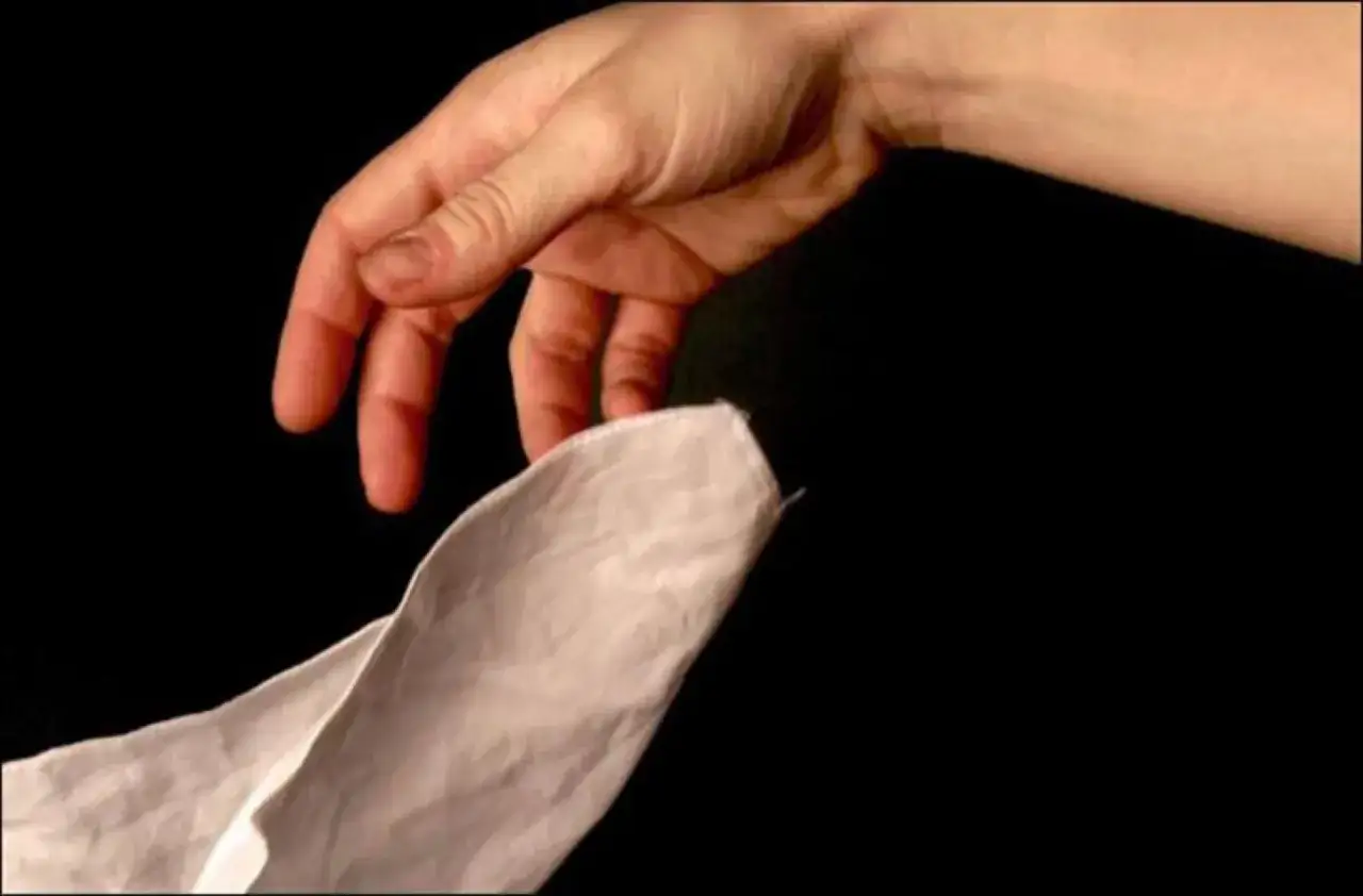 A hand reaches for a white handkerchief, a symbol of love and betrayal in the story of Othello and Desdemona.