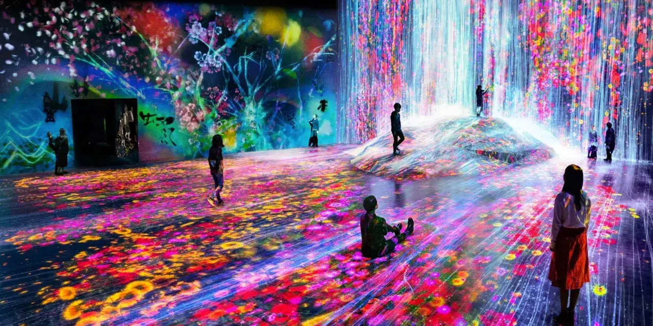 Visitors explore a digital art installation inspired by Asian artists, with projected cherry blossoms and a waterfall of light.