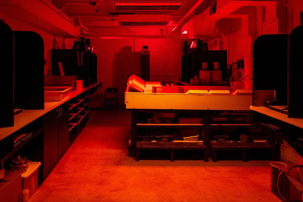 A darkroom bathed in red light, where the magic of photography in art unfolds through chemical processes and careful printing.