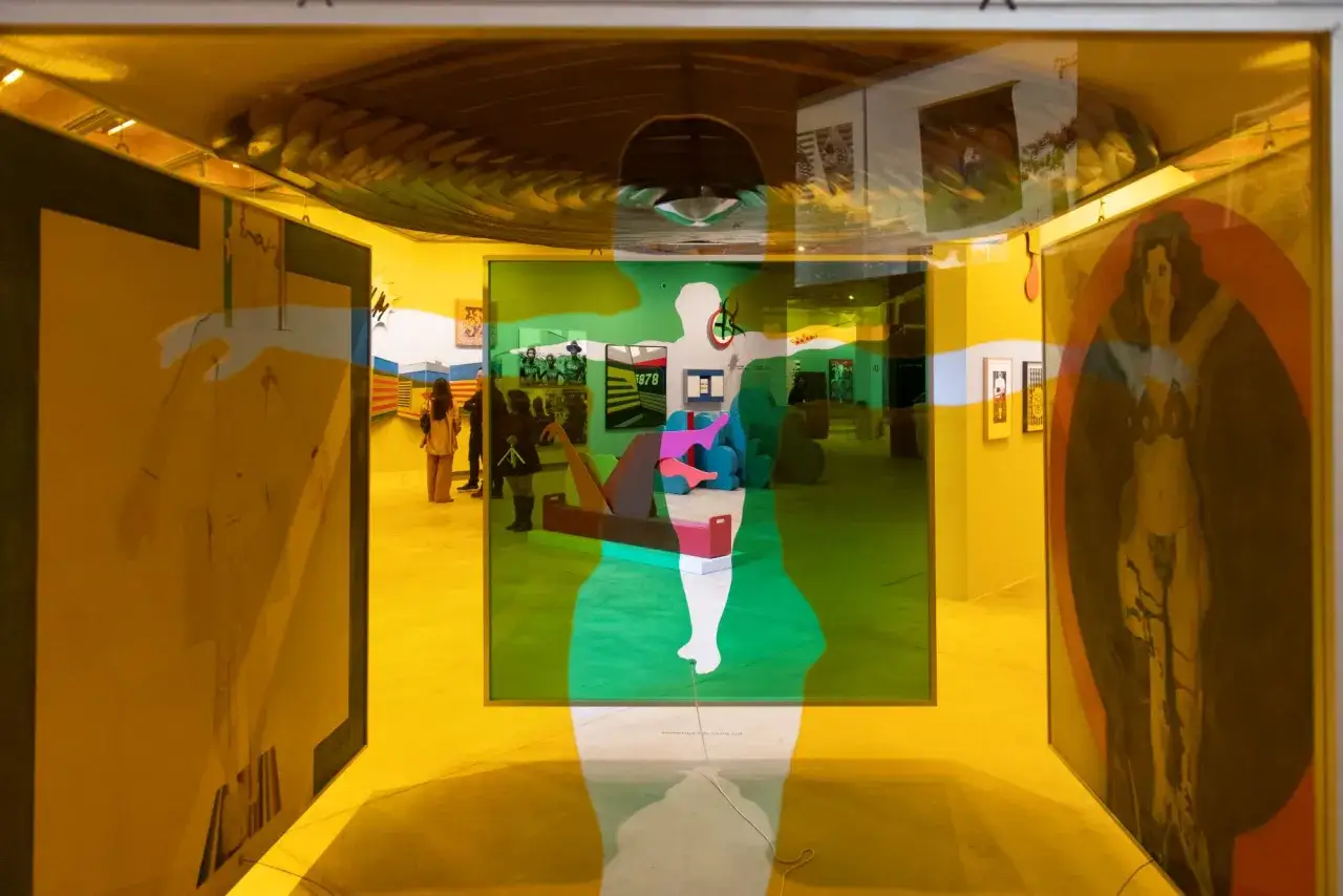 Vibrant art in Brazil, reflected through colorful glass. Figures and paintings create a surreal, layered experience.