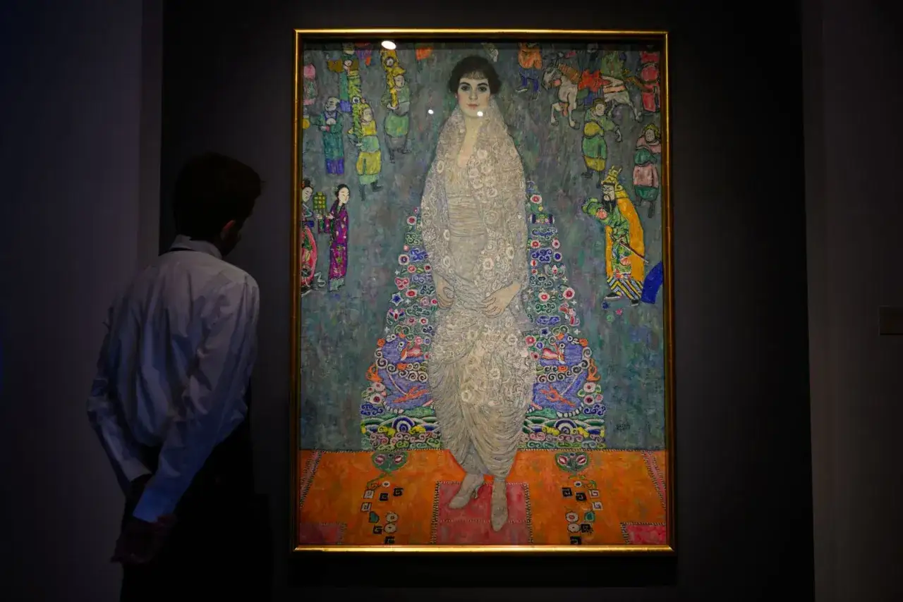 A man gazes at Adele Bloch-Bauer I, one of the most famous portrait paintings, a vibrant depiction of a woman adorned in a patterned gown.