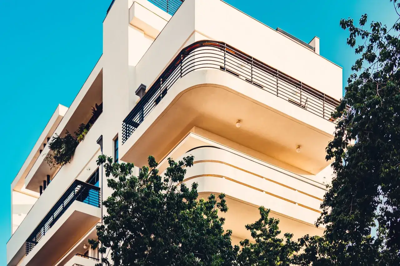Curved balconies and clean lines showcase bauhaus design examples on a modern building against a bright blue sky.